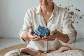 Femme tenant une pierre bleue brute entre ses mains lors d'une séance de méditation intentionnelle
