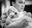 man in gray shirt carrying baby in grayscale photography