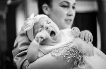 man in gray shirt carrying baby in grayscale photography